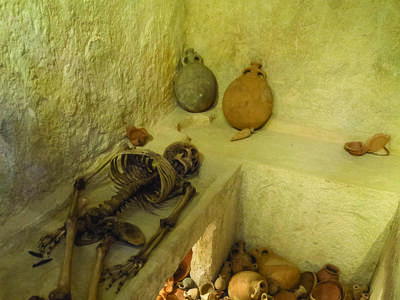 Burial Chamber from Ketef Hinnom Cemetery Interior room with ledges, one of which holds a skeleton, and a floor covered with pottery.