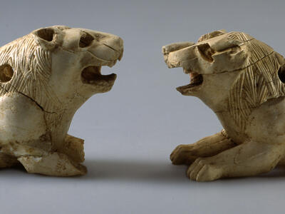 Two ivory lion figurines with open mouths and small holes throughout.