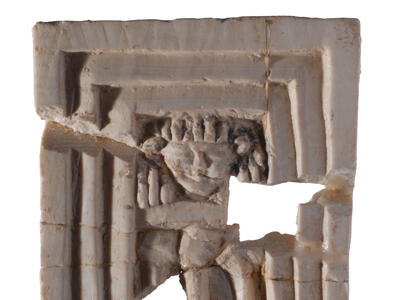 Square-shaped ivory relief of a face in a triple-recessed frame.