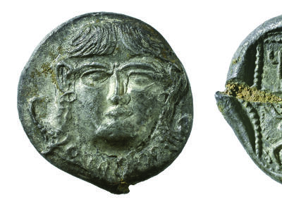 Front and back of coin, with image of face on front of coin and lion, bovine, and Hebrew inscription on back.
