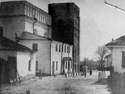 Exterior photograph of street with several buildings on left and one on right. 