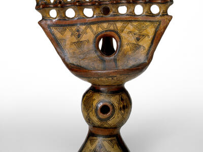 Oil lamp with geometric carvings.