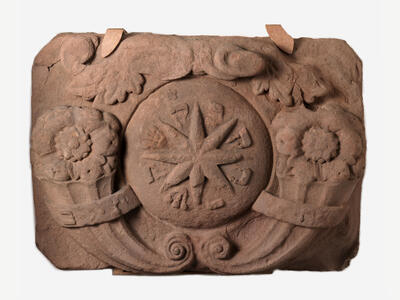 Stone with carving of star in center and flowers on either side.