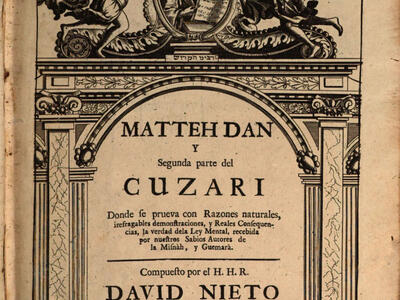 Printed page of Spanish text under decorative, columned archway with lintel featuring winged men with helmets holding banners on either side of portrait of bearded man holding a book.