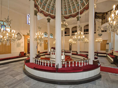 Room interior with central podium with tall columns and many chandeliers surrounding.
