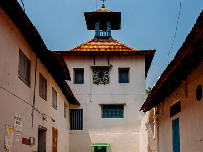Exterior photograph of intersecting walls of stone buildings with tile roofs.