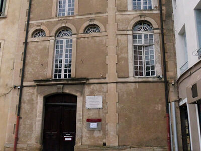 Exterior photograph of building facade with arched windows. 