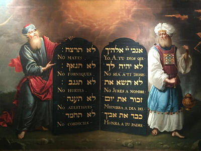 Painting of two bearded men in robes, one on each side of large tablets with Hebrew and Spanish text. 