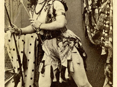 Full body portrait of woman with legs slightly bent and body shifted to one side in an active pose, wearing armor. 