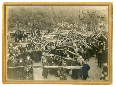 Photograph depicting a crowd of people holding a long ribbon with Russian text on it.