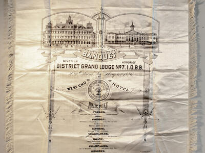 Cloth with image of buildings and menu in English printed on it.