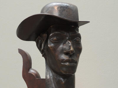 Bust of man wearing a hat.
