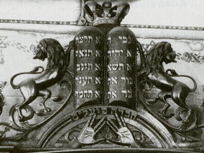 Photograph of wooden structure with two small columns of Hebrew writing with crown on top, and two sculped lions on either side.