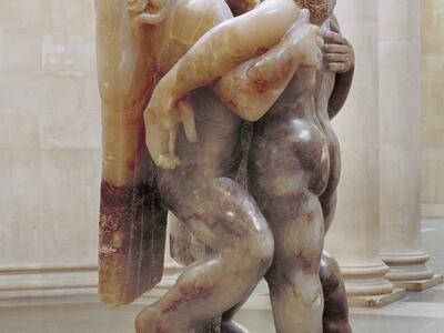 Sculpture depicting angel and man, both upright, with arms around each other.