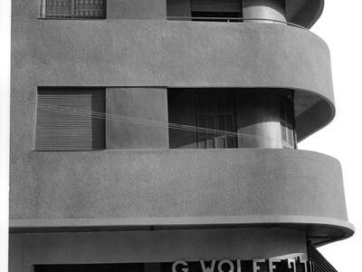 Photograph of side of three-story building exterior featuring sleek, curved balconies.