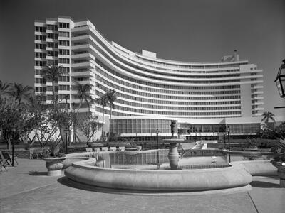 Fontainebleau Hotel, Miami Beach, Florida. Over Pool to Hotel. Florida, Miami Beach Photograph of curved exterior of a hotel with pool and fountain in the middle.