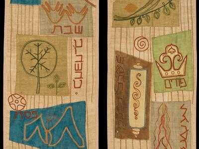Textile featuring two panels depicting Torah scrolls, Hebrew words, candles, scale, geometric shapes, and floral and plant motifs.