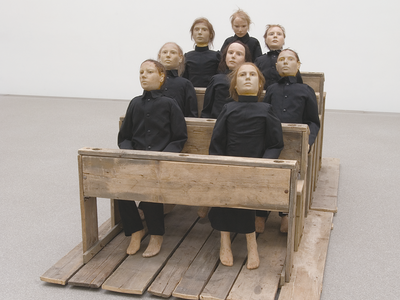 Art installation of eight figures sitting on pews. 