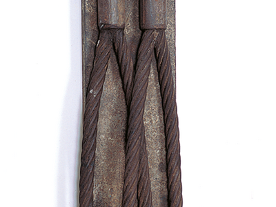 Industrial iron sculpture with two curved cords that meet at the top.