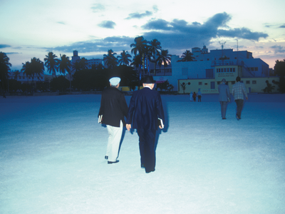 Photograph depicting people walking toward buildings, away from the camera. 