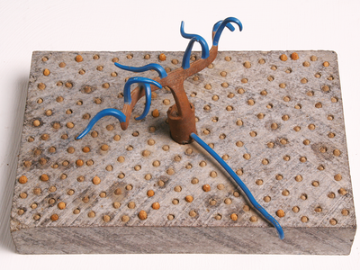 Abstract sculpture featuring iron lines protruding from cement base covered in small circles.