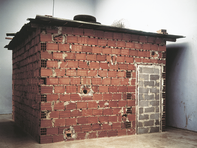 Installation depicting doorless and windowless brick structure. 