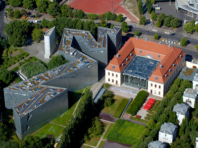 Aerial photograph of angular buildings with trees and grass surrounding. 