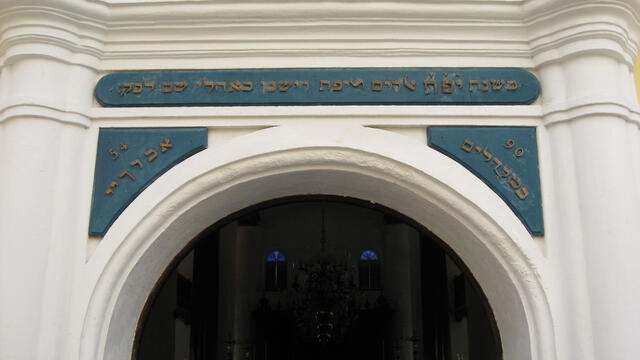 Photograph of arched entrance to building with Hebrew over lintel. 