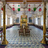 Photograph of room with floor tiles, two gold columns, and glass chandeliers.