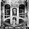 Photograph depicting tall statue in the center of large atrium with interior staircases.